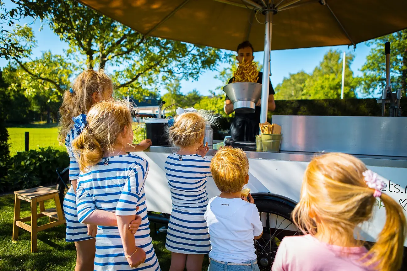 Kinderen bij frietfiets voor een puntzakje friet