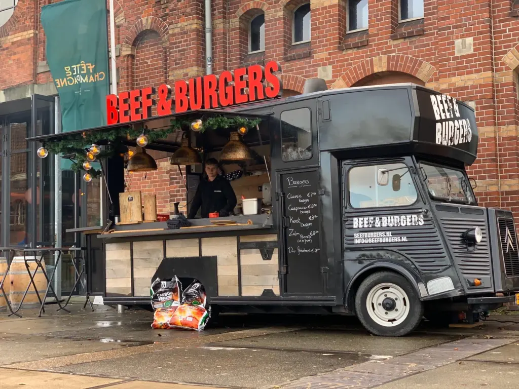 Zwarte Citroen HY foodtruck Beef and Burgers voor een bakstenen pand