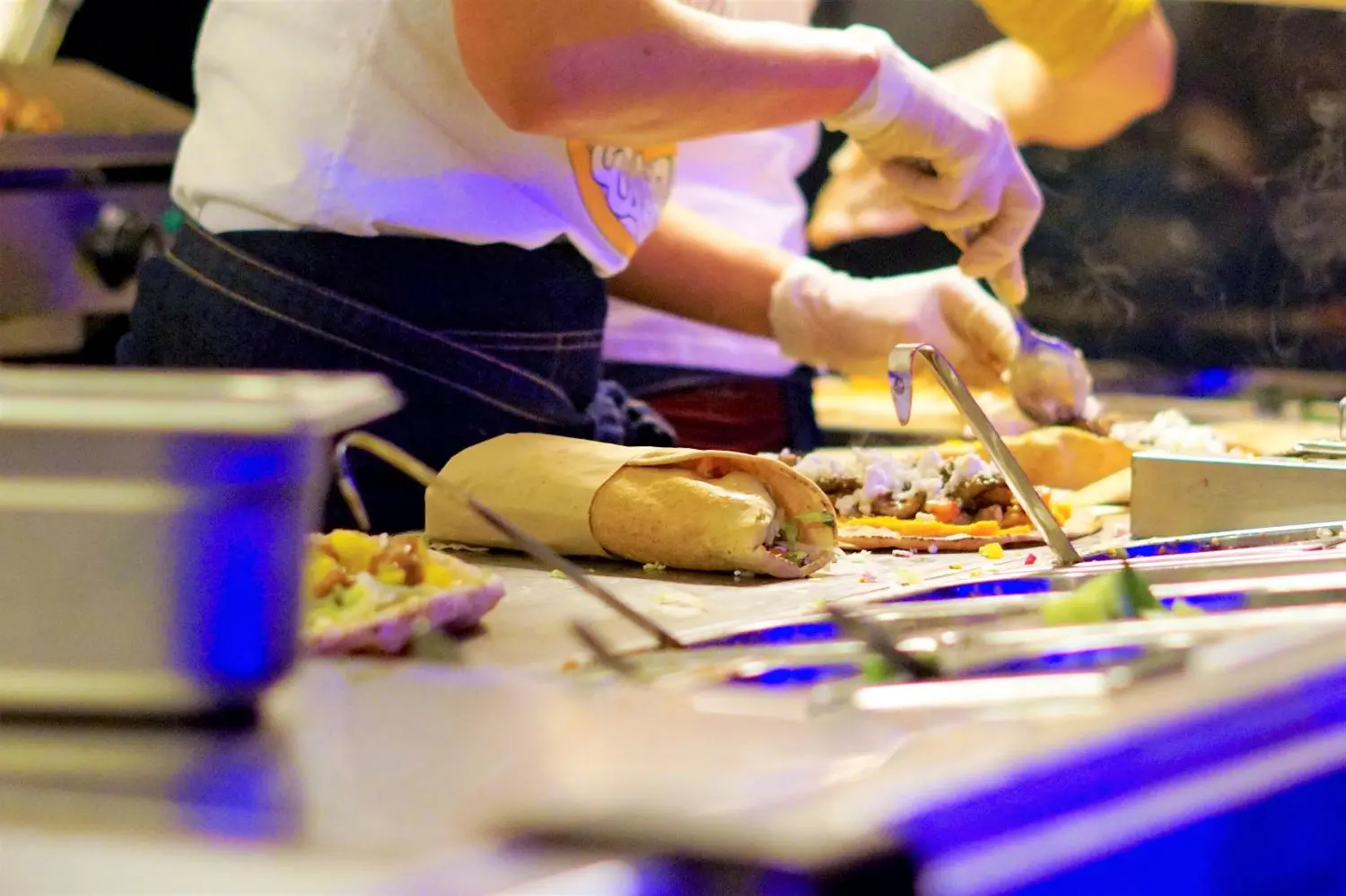 Medewerkers beleggen wraps op een verlichte werkbank in een foodtruck