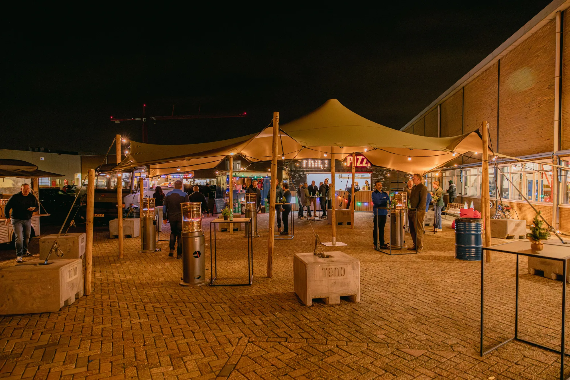 Bedrijfsfeest op een parkeerplaats met verlichte stretchtenten in de avond
