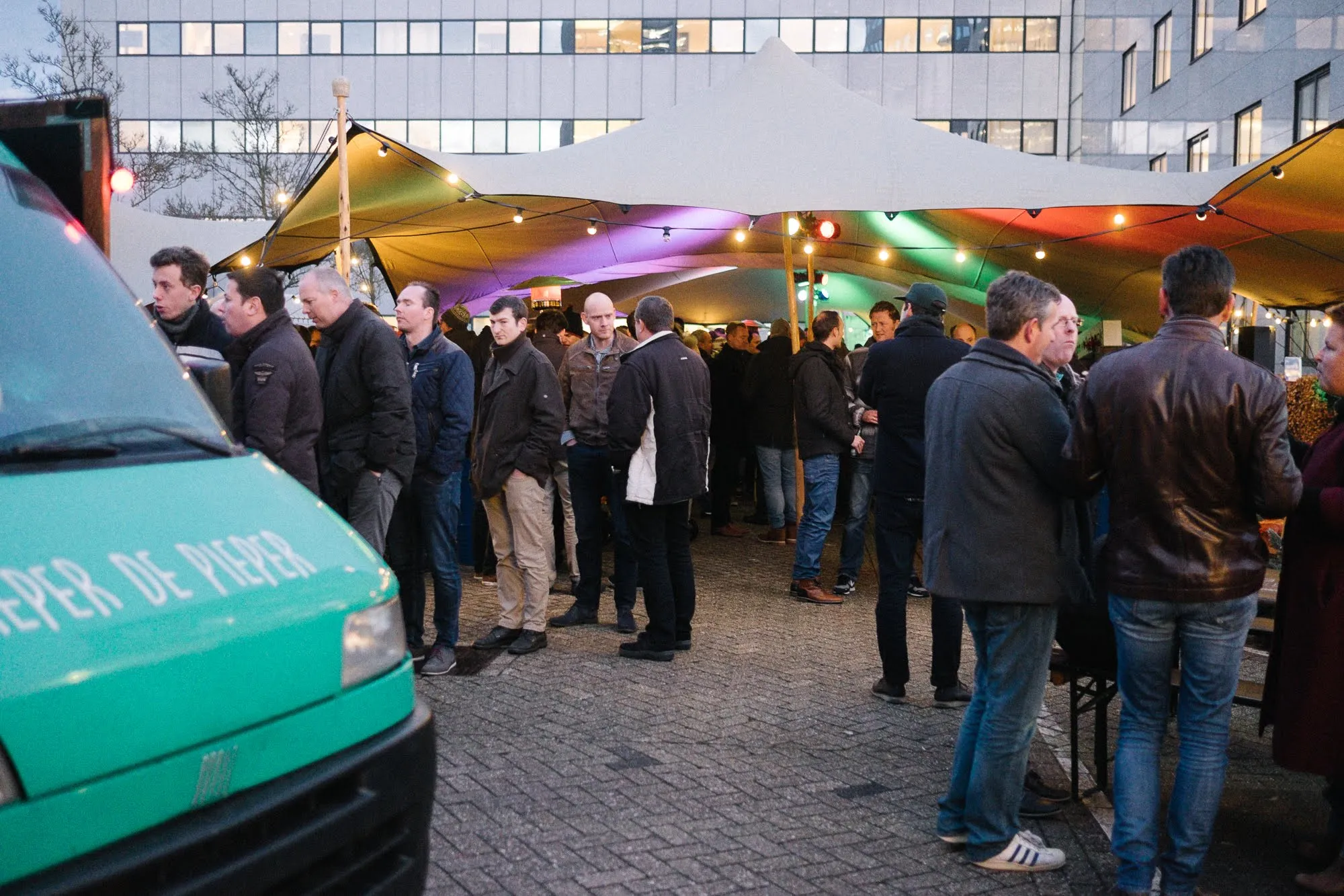 Gasten in winterjassen bij een verlichte stretchtent tijdens een bedrijfsfeest