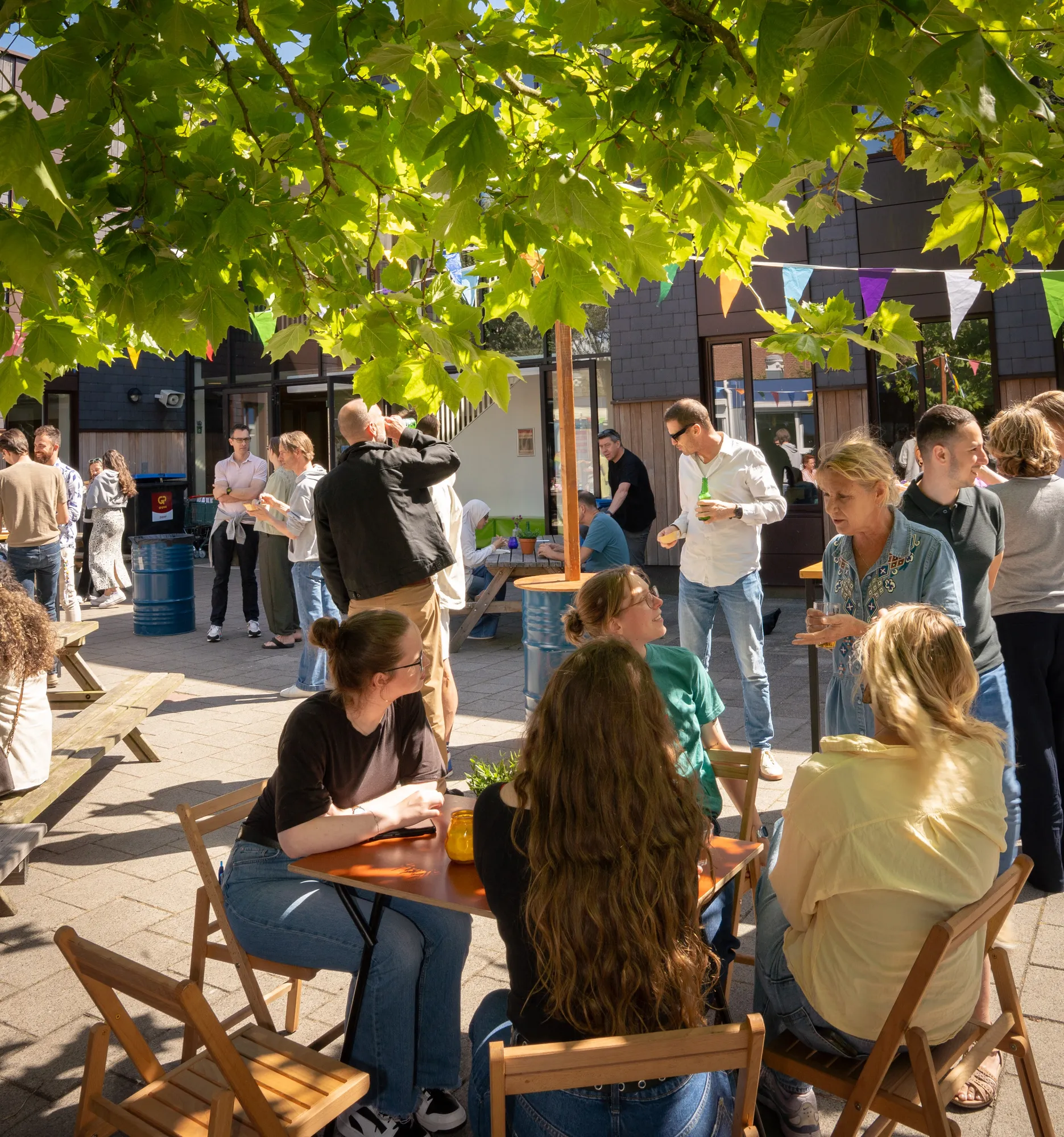 Terras met houten tafels en stoelen onder de bomen tijdens een foodtruckfestival