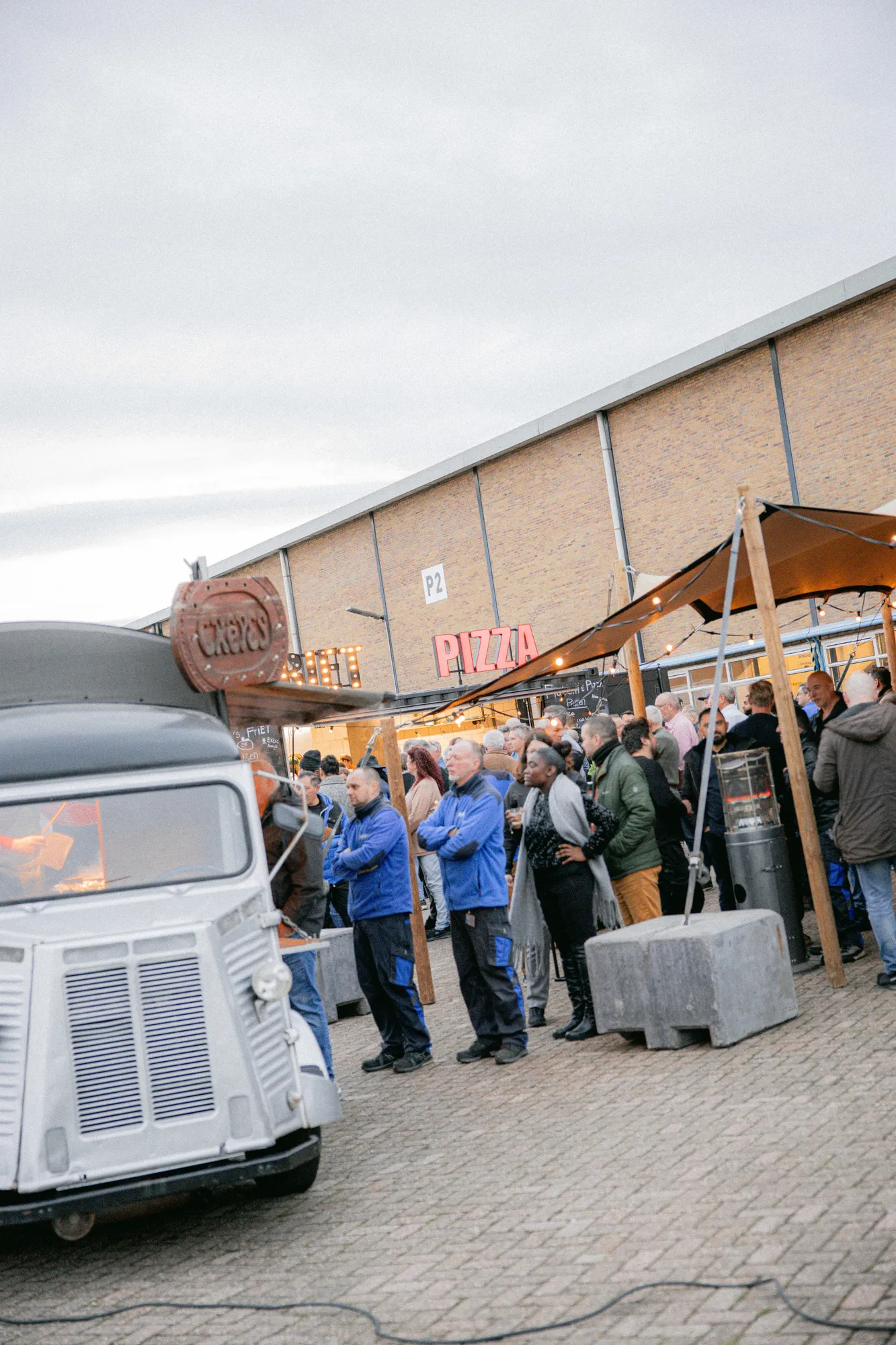 Vintage crêpetruck met wachtende gasten bij een loods tijdens een winterevenement