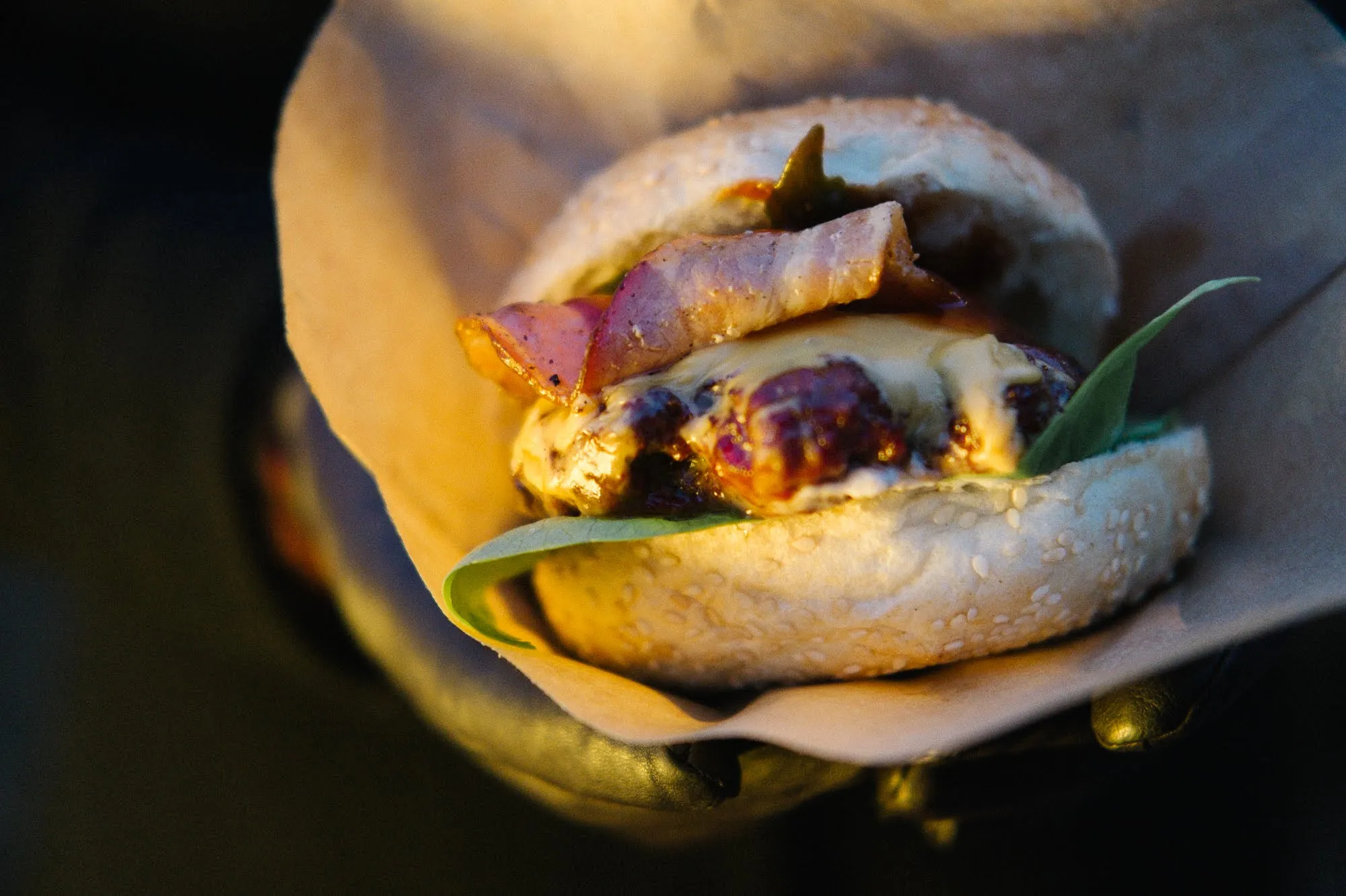 Close-up van een burger met spek en gesmolten kaas in papier