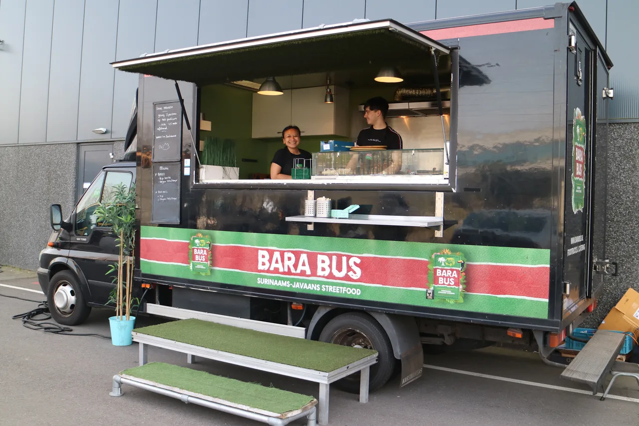Zwarte Bara Bus foodtruck met medewerkers in het uitgifteluik