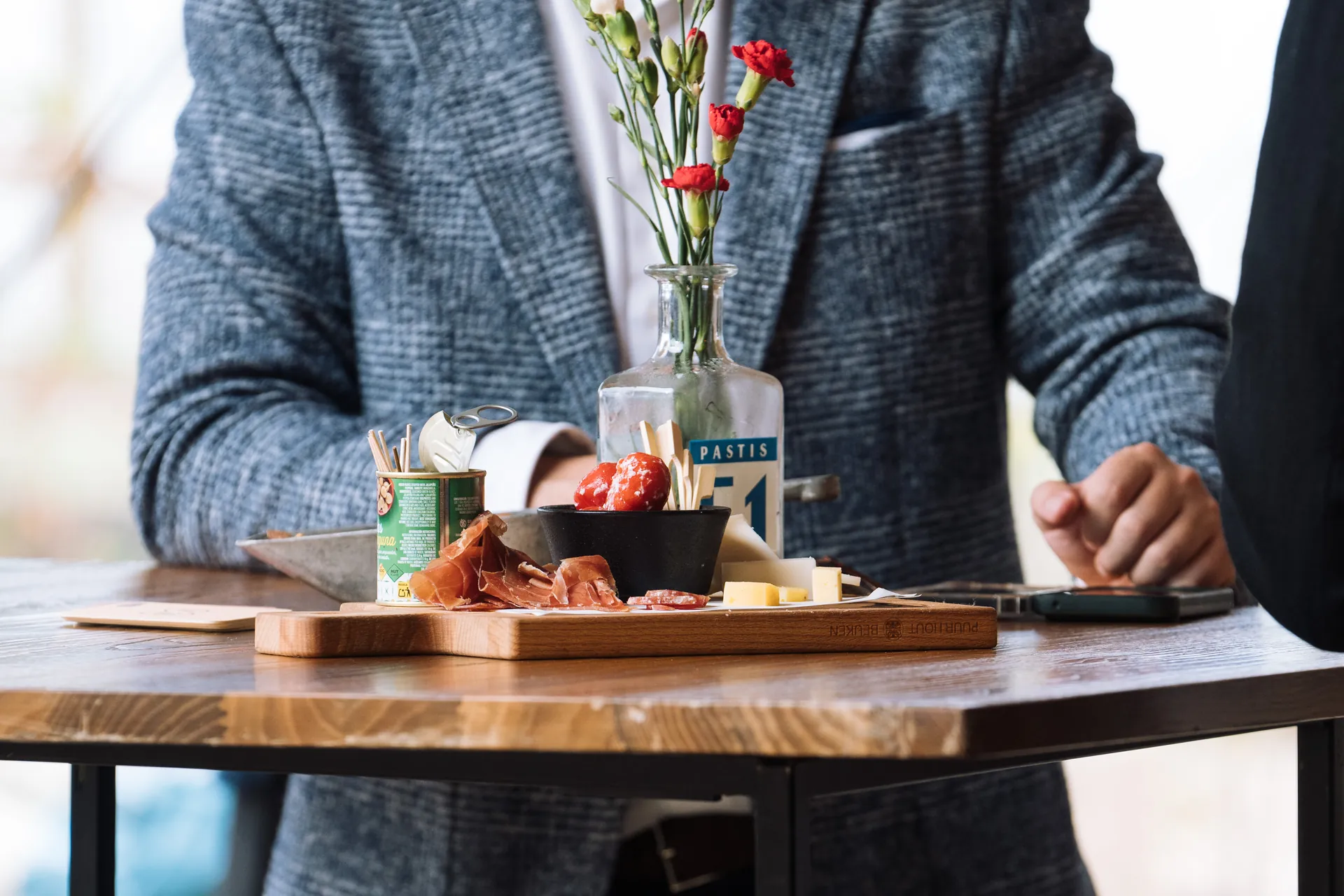 Borrelplank met ham, kaas en peppadews op een statafel tijdens een vrijdagmiddagborrel