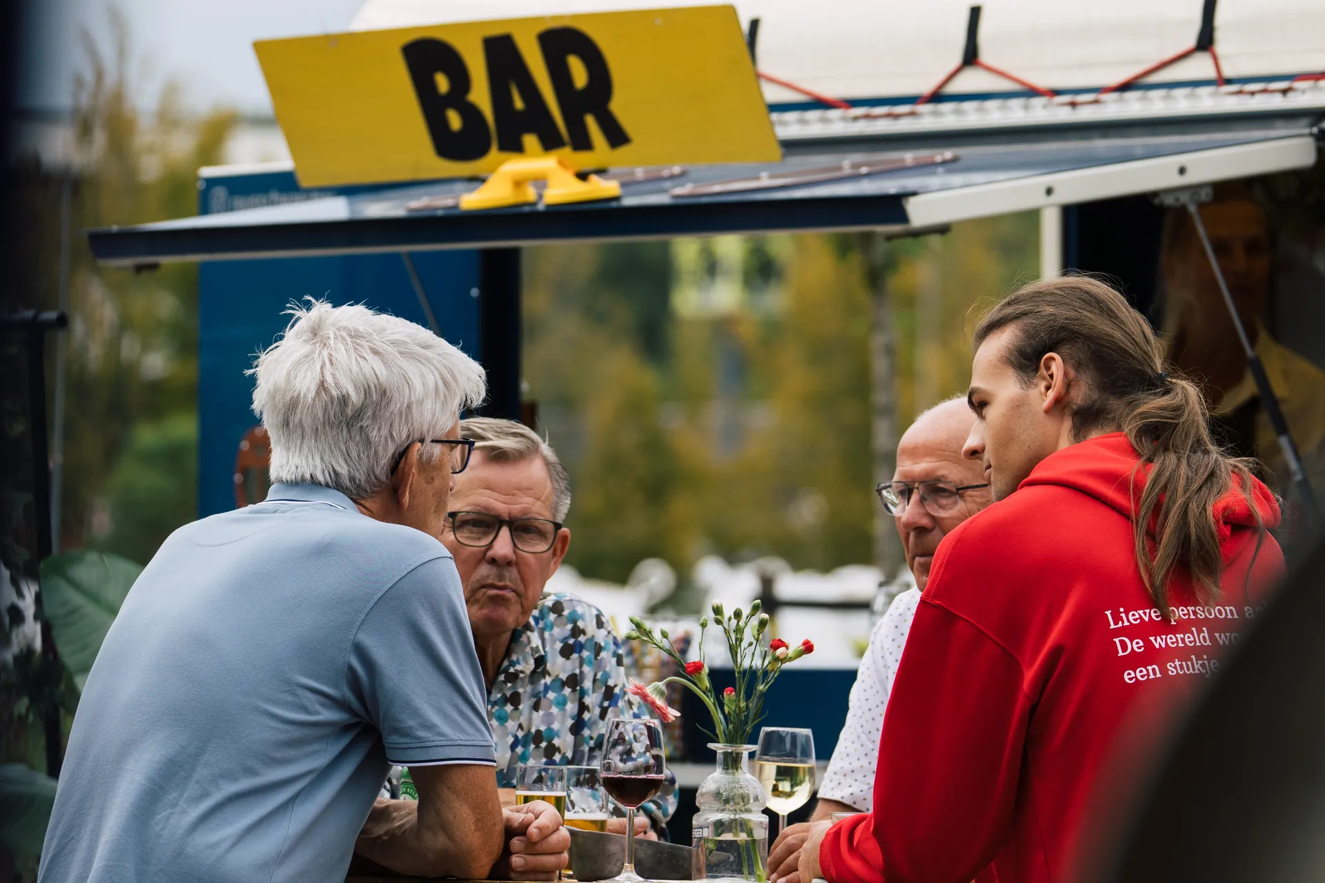 Gasten aan een statafel bij de mobiele bar van Festibar tijdens een bouwevent