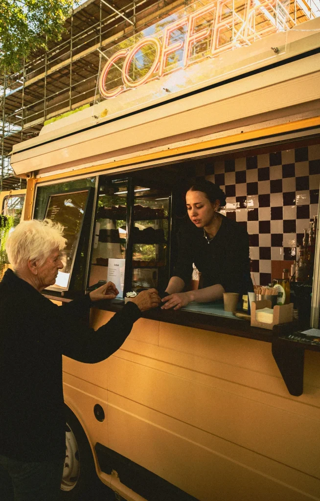 Barista van Kuub Coffee Events serveert koffie aan een gast vanuit de koffietruck